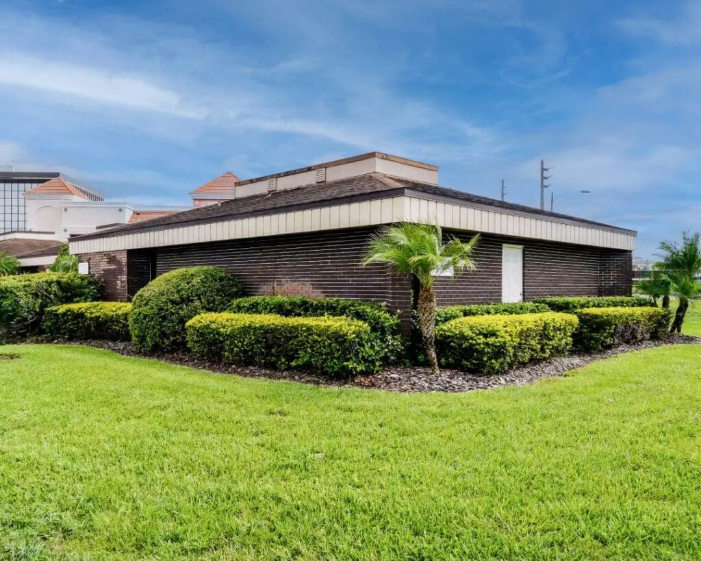 Podiatrist Orlando office near Universal with a modern dark brick exterior, a single palm tree out front, and manicured green shrubbery.