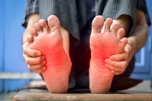 A close-up of a person's feet displaying red spots, indicating pain.